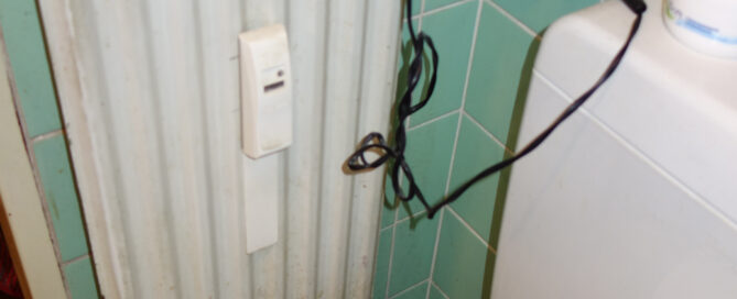 Ein verrosteter Heizkörper neben einem WC.