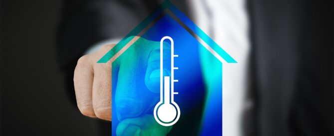 Mann tippt mit Finger auf ein Thermostat in einem Haus
